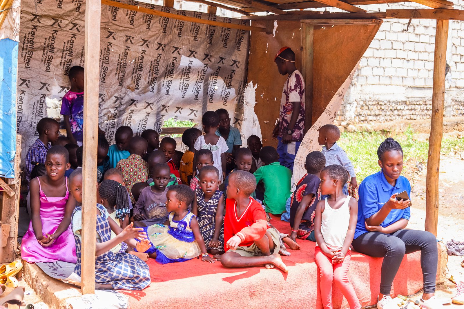 Children gathered under a shelter with one of our volunteers