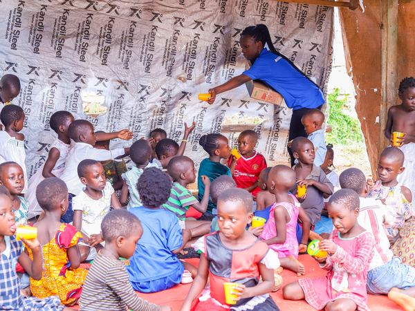 Children sitting together under a shelter with their drinks