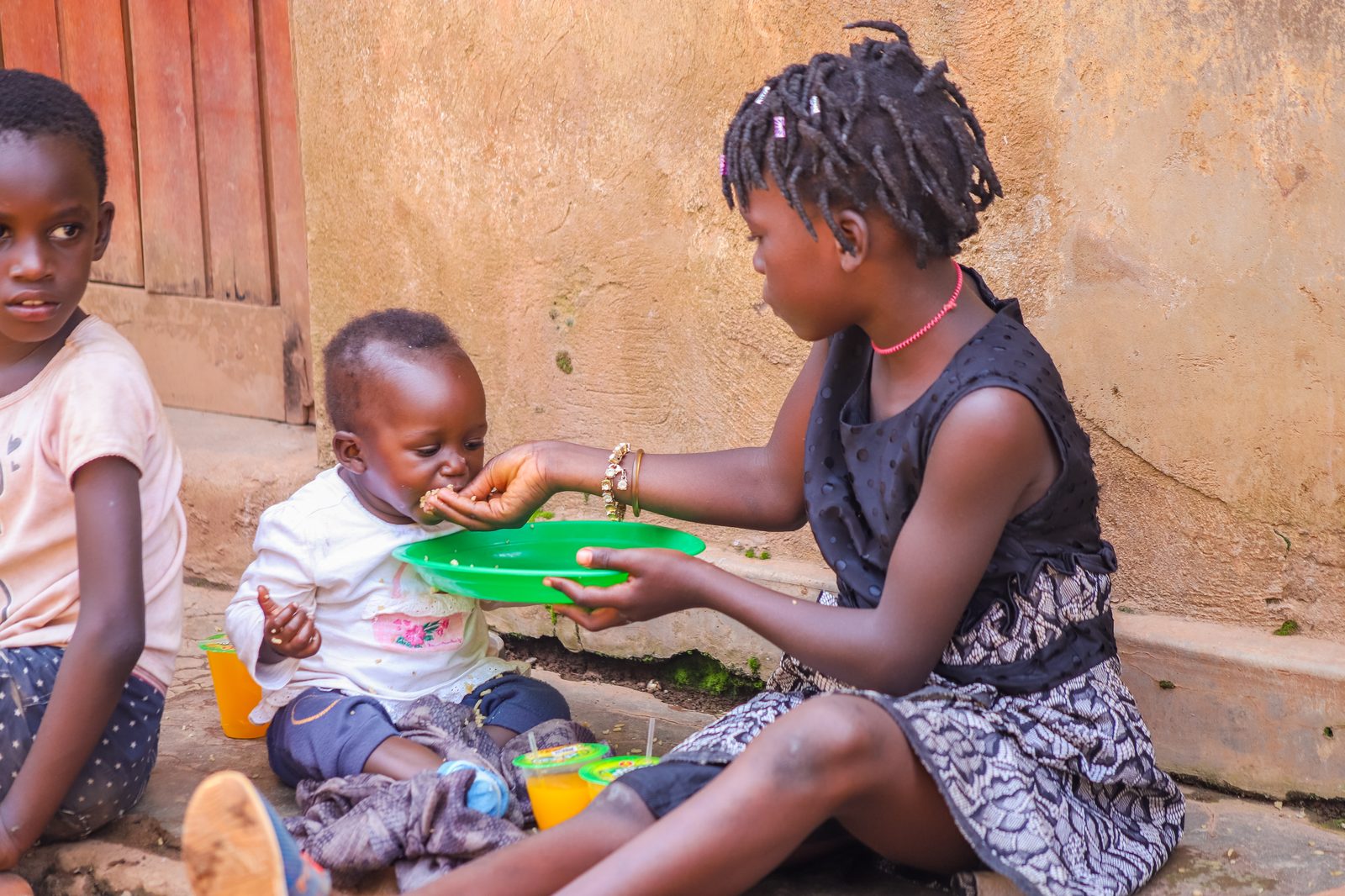 An older girl feeding a toddler at one of our outreach days