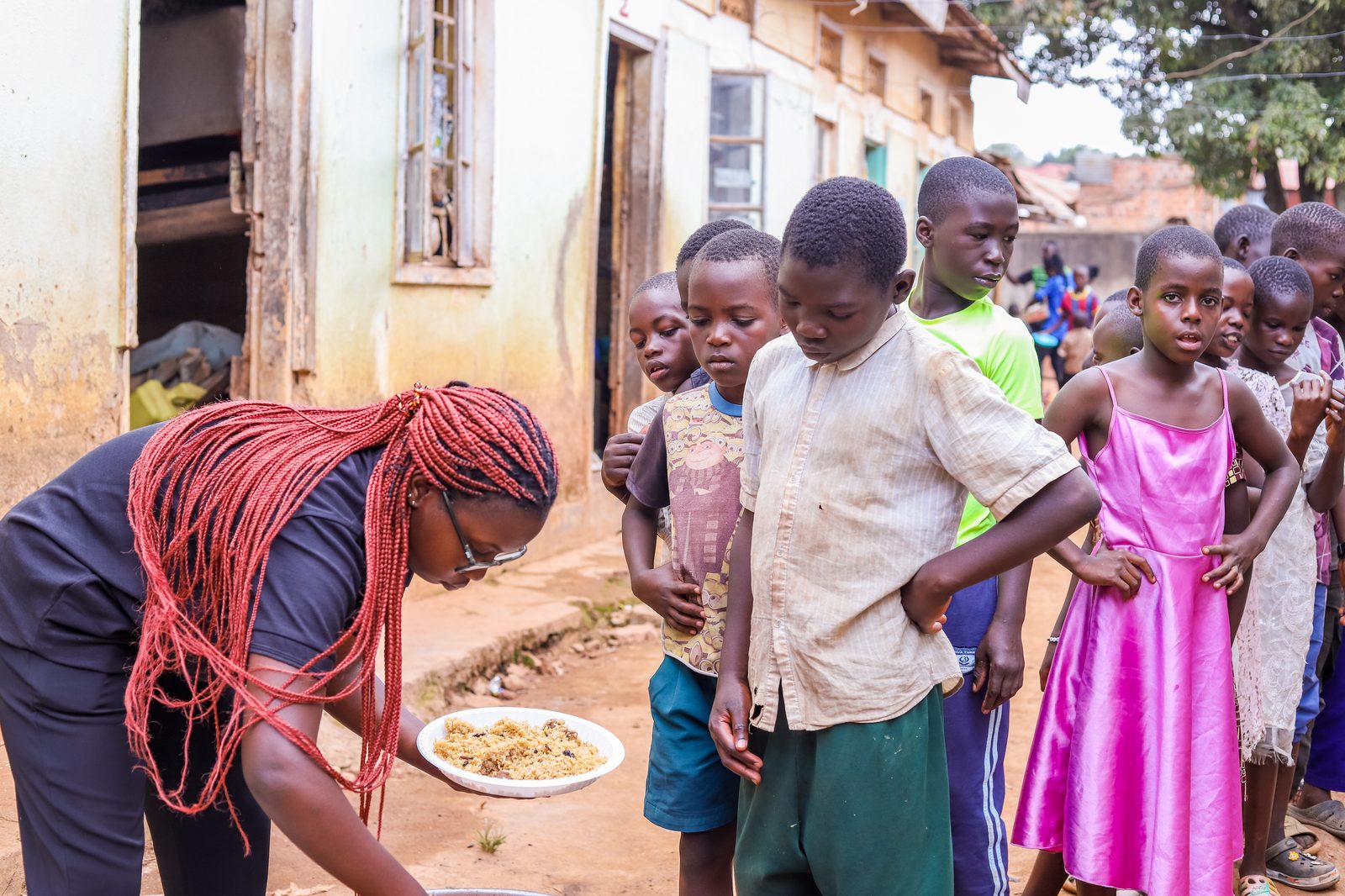 A volunteer serving a plate of food to children